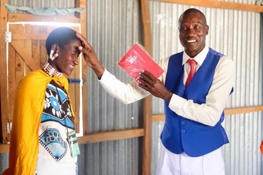 Pastor Moses greets a lady the Maasai way (with a pat on the head)